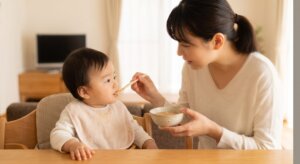 日本人の赤ちゃんに離乳食用に柔らかく煮込んだ牛タンをスプーンで与える母親。