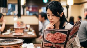 焼肉店でメニューの牛タンの写真を見つめる日本人女性